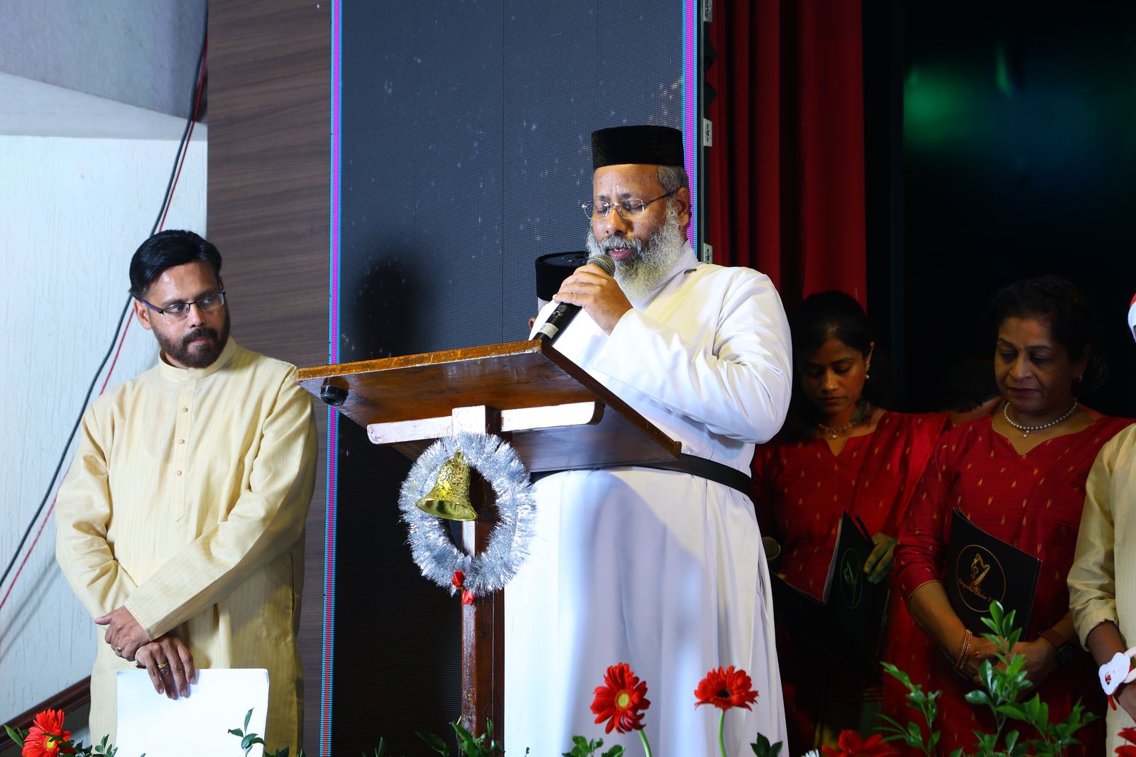 Clergy speaking at the podium with attendees looking on